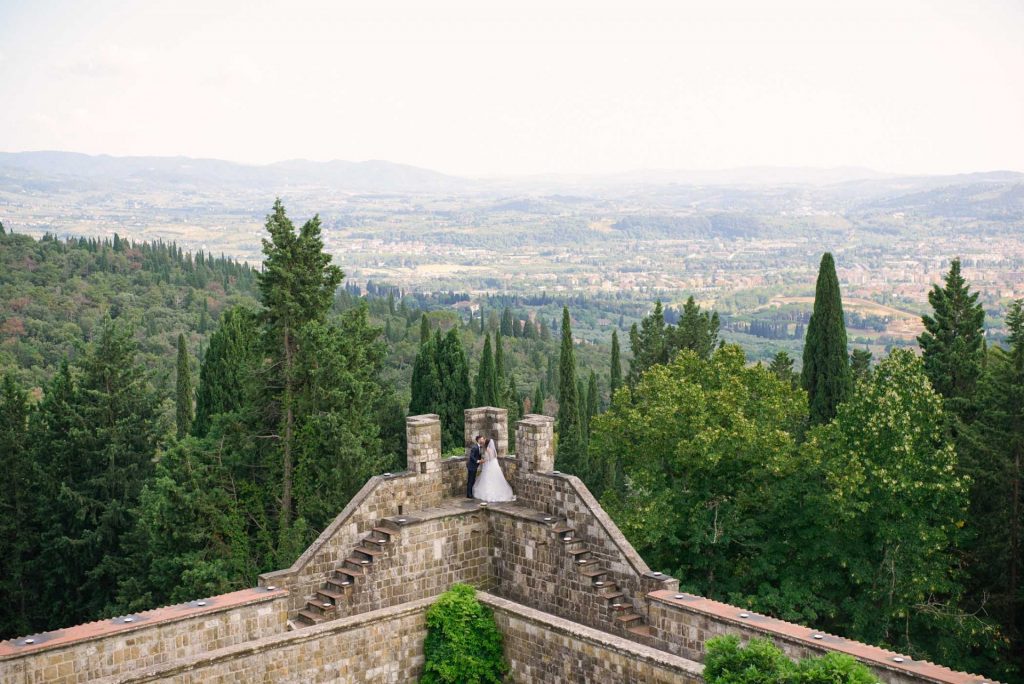 Bride and groom kissing on the edge of their Italian Castle venue overlooking views of Florence