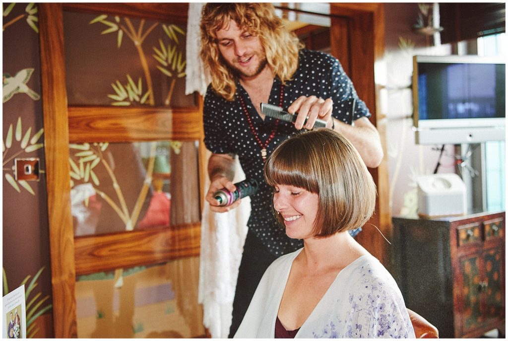 Happy bride having her hair styled in Shorditch hotel room