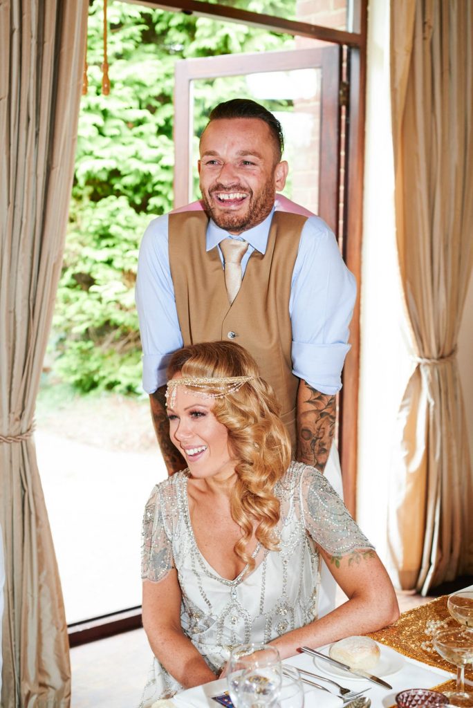 1920's style bride and groom laughing during speeches at Great Gatsby themed wedding