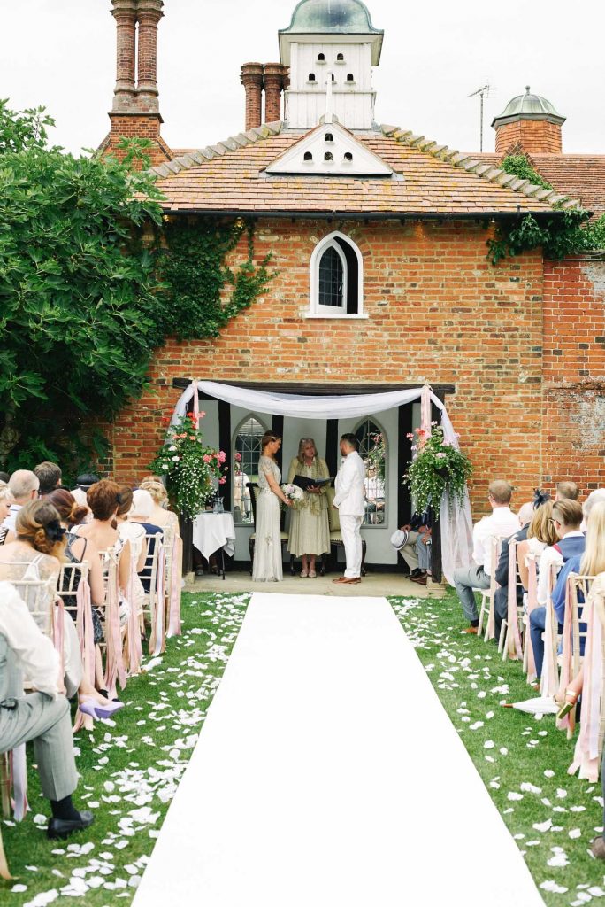 Bride & Groom stood at the end of the outdoor alter whilst friends and family watch them get married