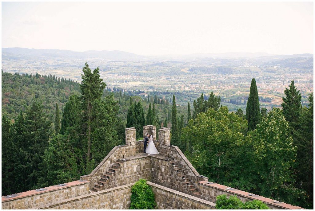 Bride and groom on the edge of Castello Di Vincigliata over looking view of Florence