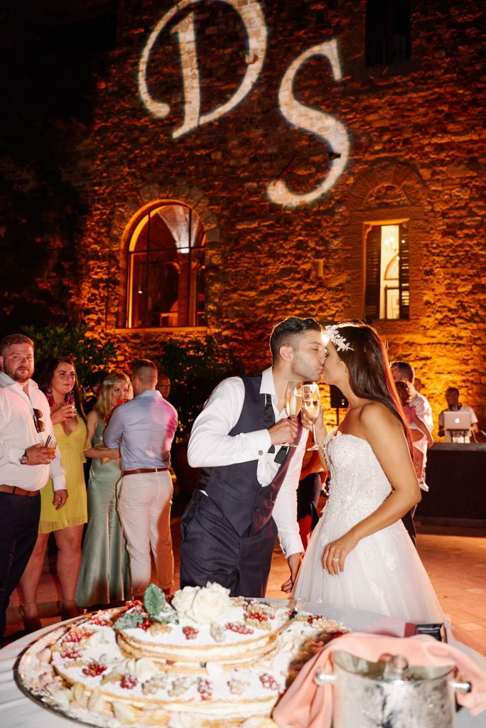 Bride and groom kissing in front of wedding cake during destination wedding at Castello Di Vincigliata in Florence