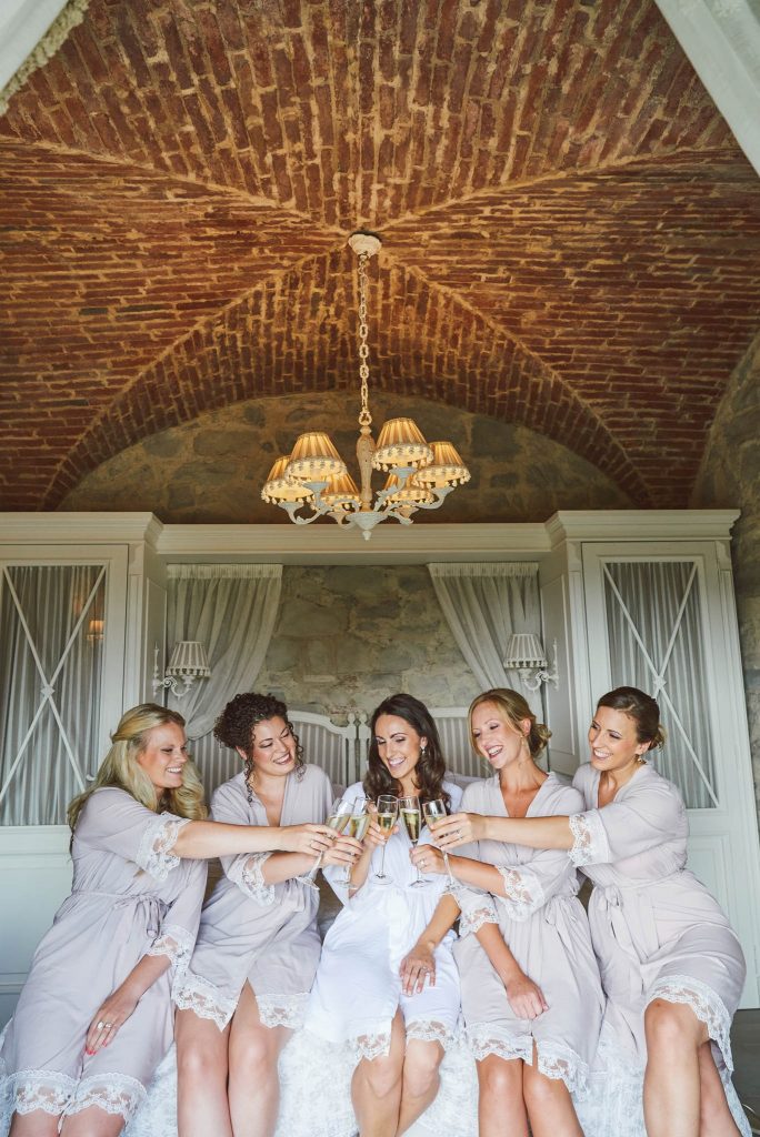 Bride and bridesmaids in dressing gowns toasting champagne at Villa le Fontanelle wedding venue in Florence, Italy