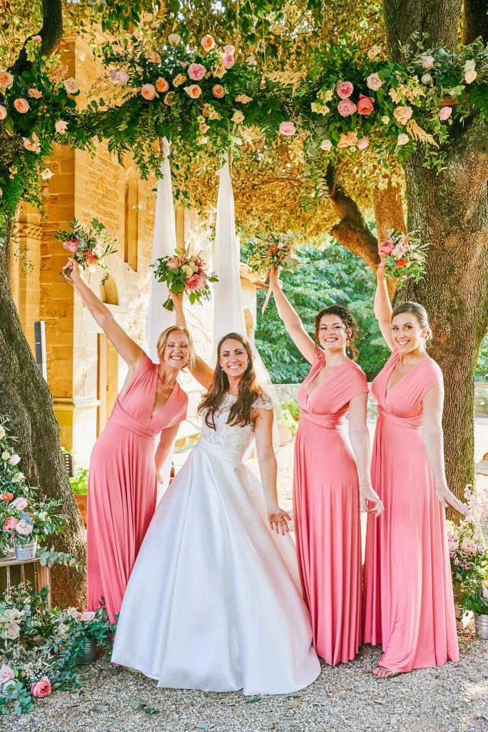 Bride with bridesmaids holding flowers in the air whilst outside at villa le Fontanelle in Florence Italy 