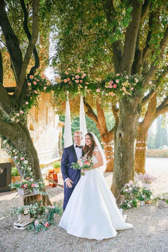 Bride and groom smiling in front of outside flower arch at the villa le Fontanelle in Florence Italy