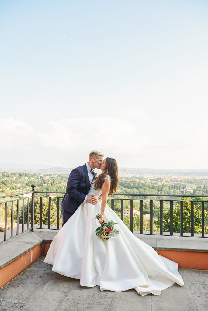 Bride and groom kissing in front of a stunning Tuscany view point 