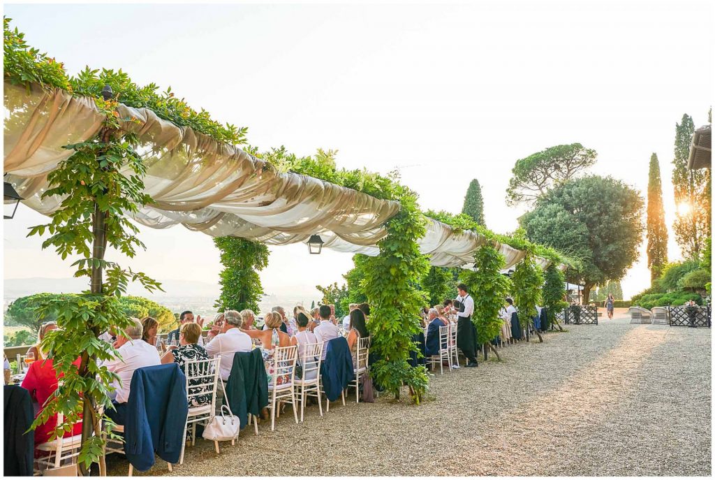 Wedding guests sat outside at dinner overlooking a stunning view of Tuscany at Villa Le Fontanelle