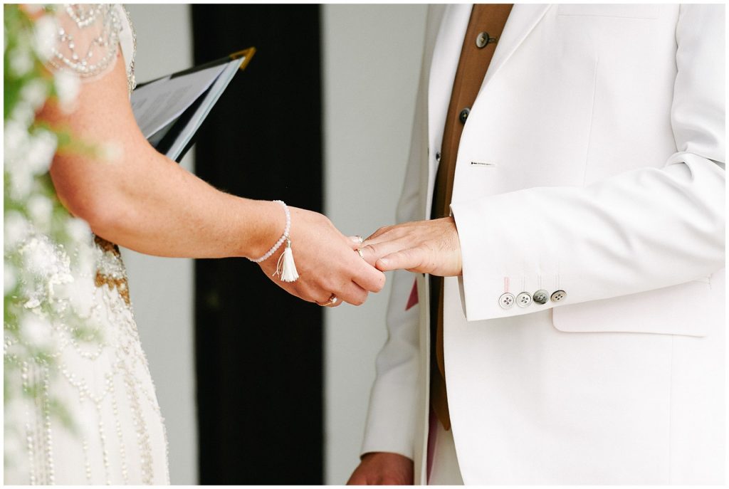 close up of bride and grooms hands during outdoor wedding ceremony