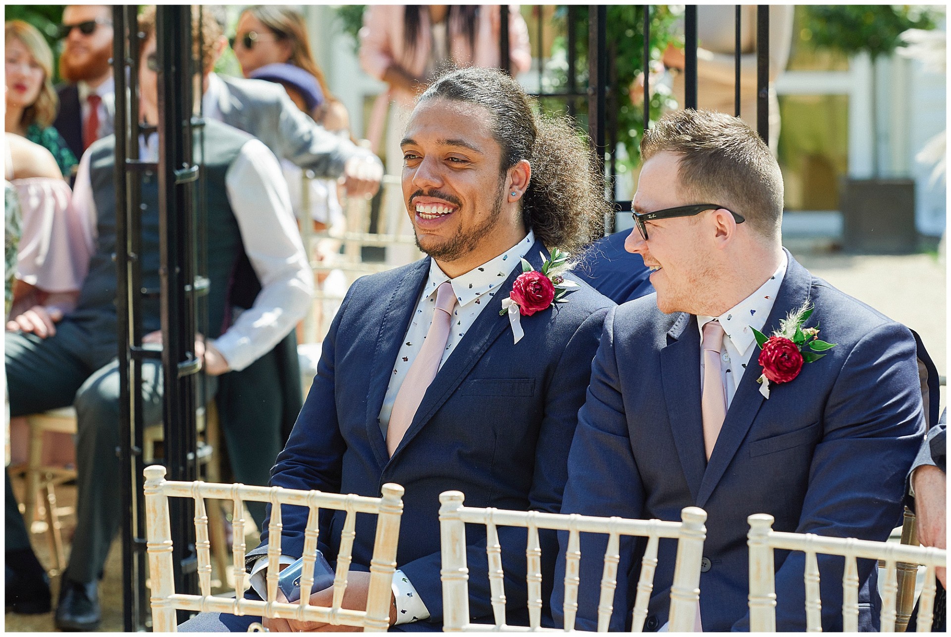 Groomsmen sat outside laughing during outdoor wedding ceremony