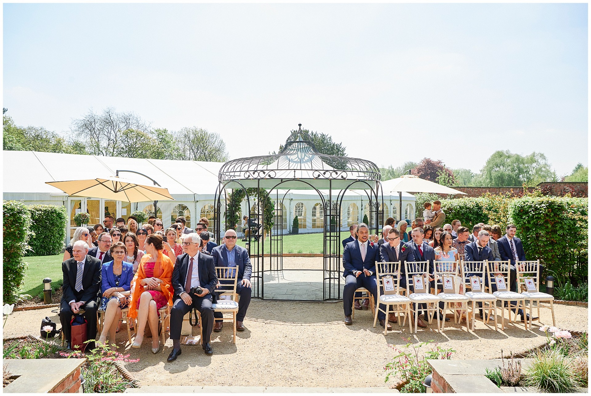 Bridal party sat outside during a sunny outdoor wedding ceremony at The Walled Garden in Beeston.