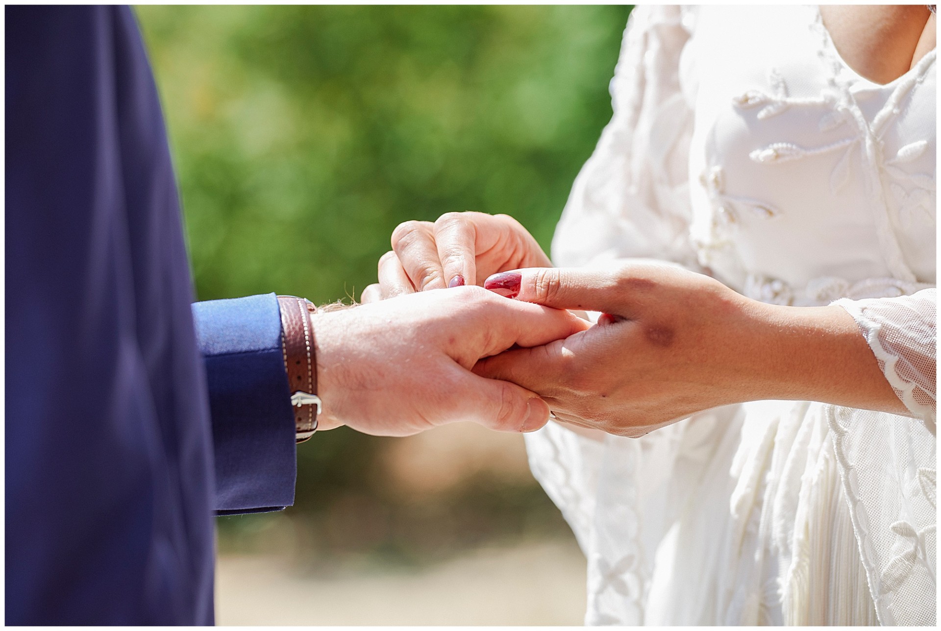 Close up of hands exchanging rings during outdoor wedding ceremony at the Walled Garden in Beeston