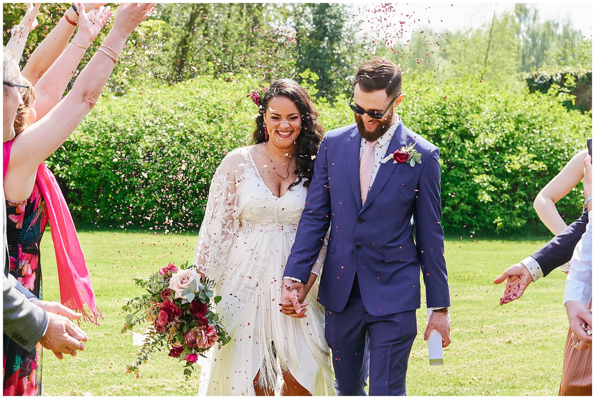 Bohemian bride and groom walking through confetti at The Walled Garden in Beeston