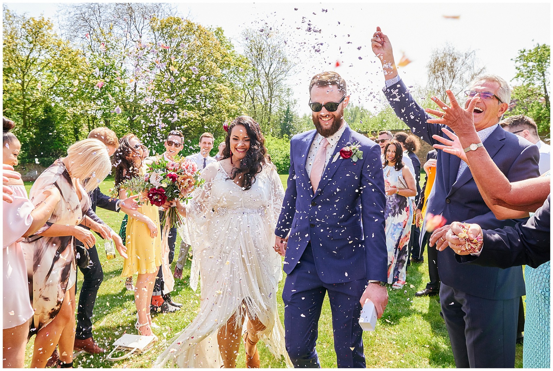 Boho style bride and groom walking through confetti during Nottingham wedding 