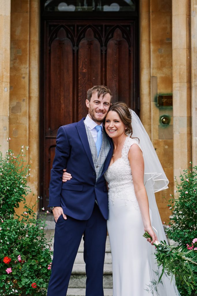Bride and groom smiling together outside of Westminster church in London 