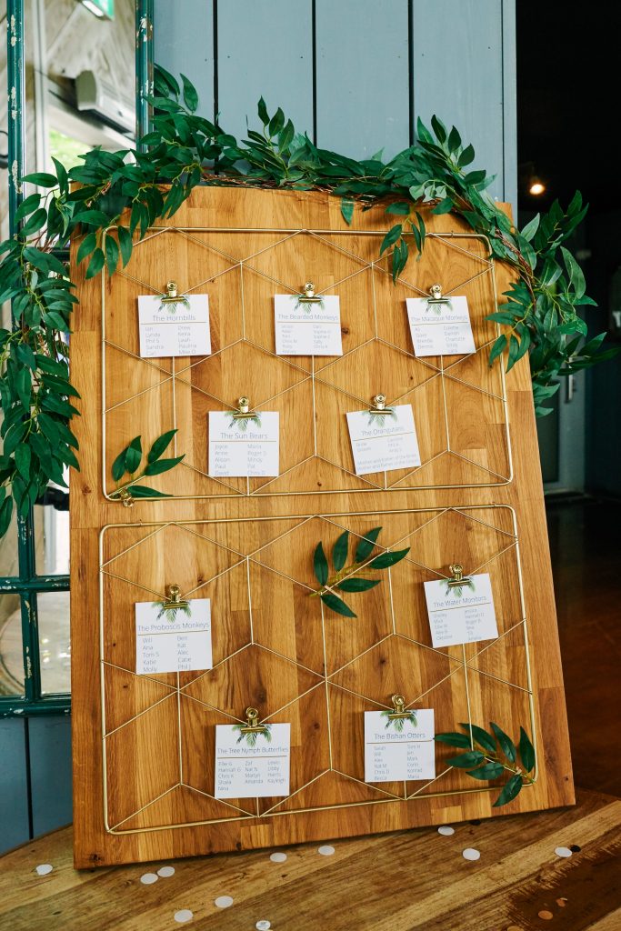 Wedding table plan on plank of wood with pegged paper on it. 