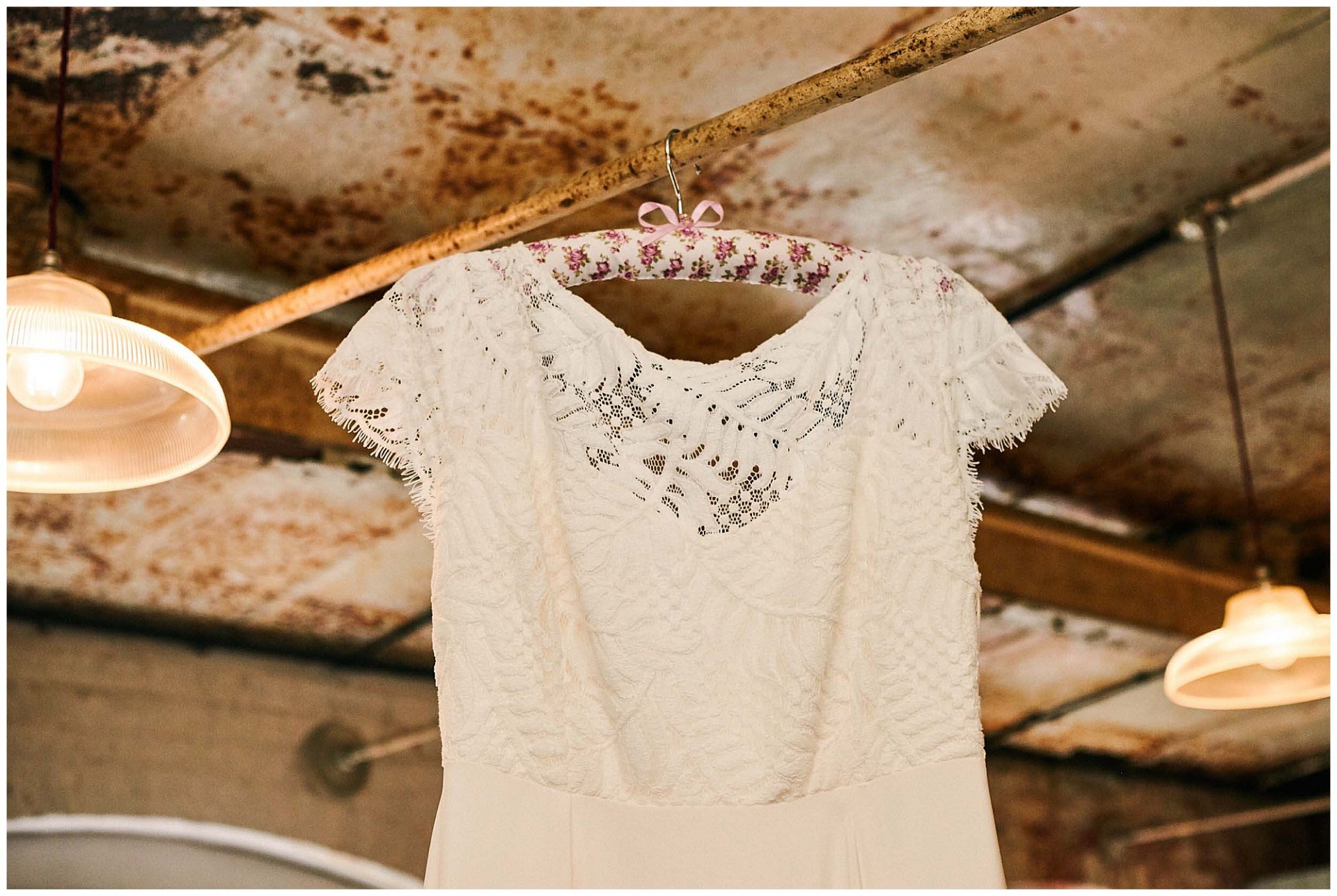 Brides wedding dress hung up against a rustic metal background at The West Mill