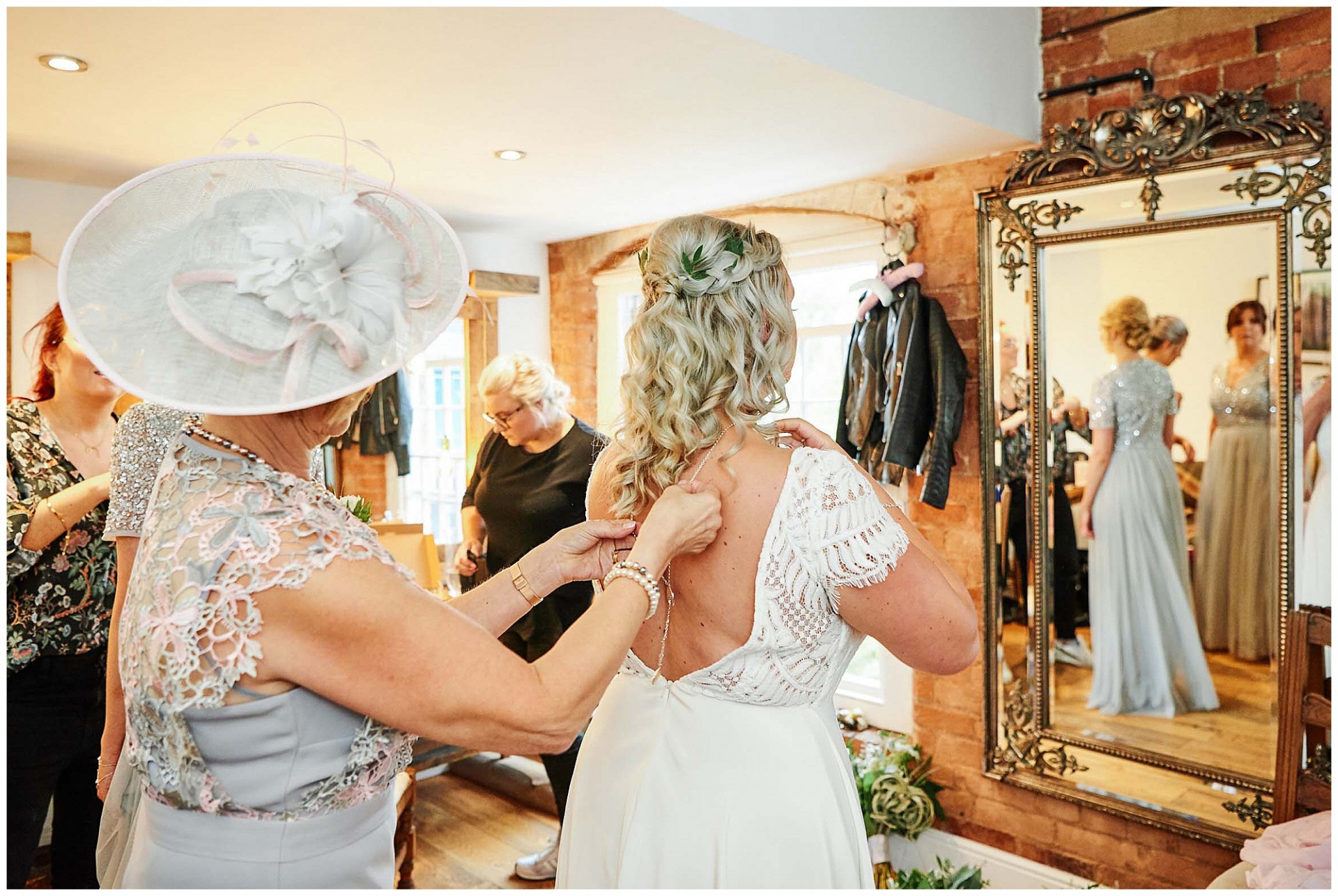 Brides mum helping bride put on her jewellery in the dressing room at The West Mill Wedding Venue