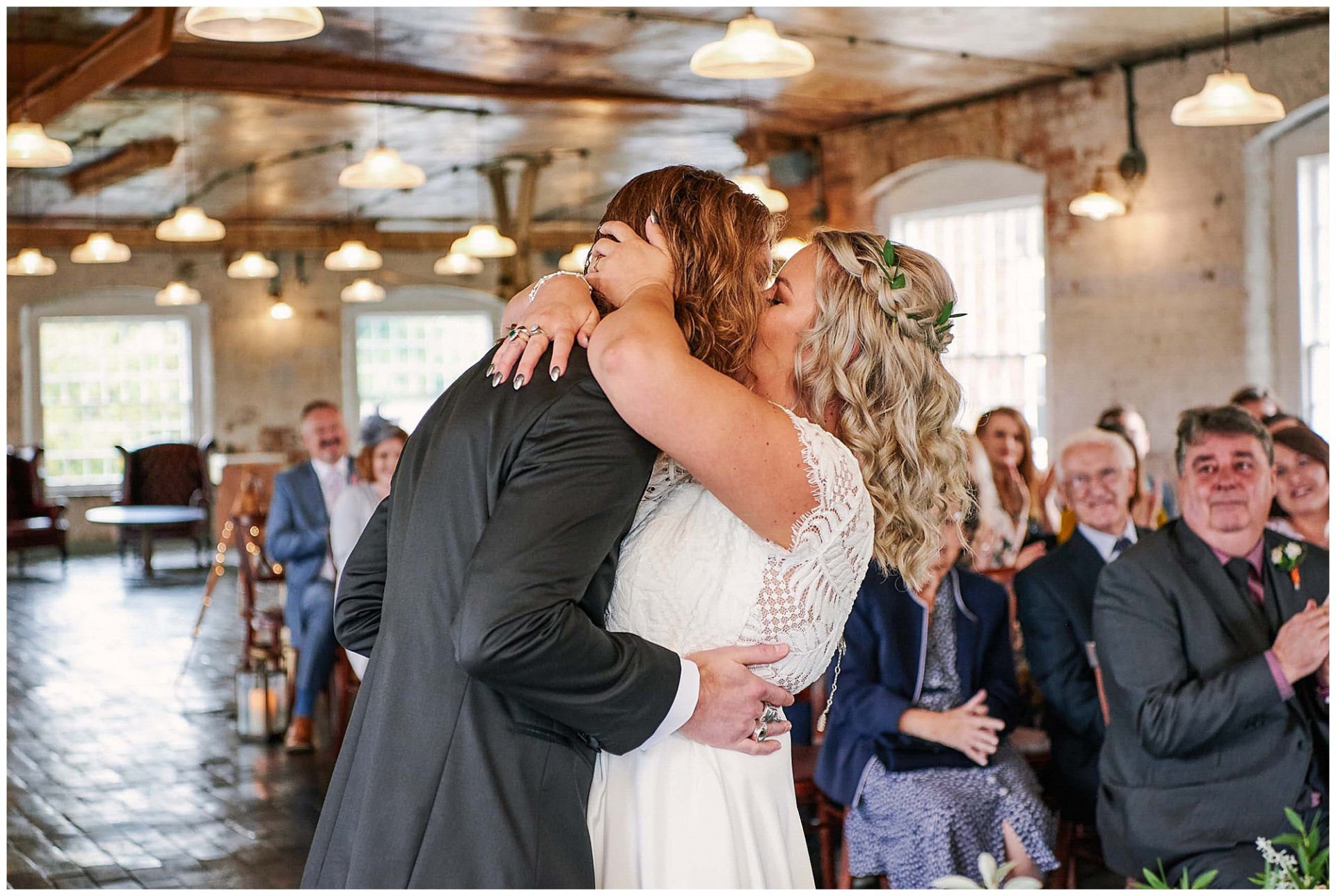 Bride and grooms kissing during their wedding ceremony at the industrial  West Mill Venue in Derby