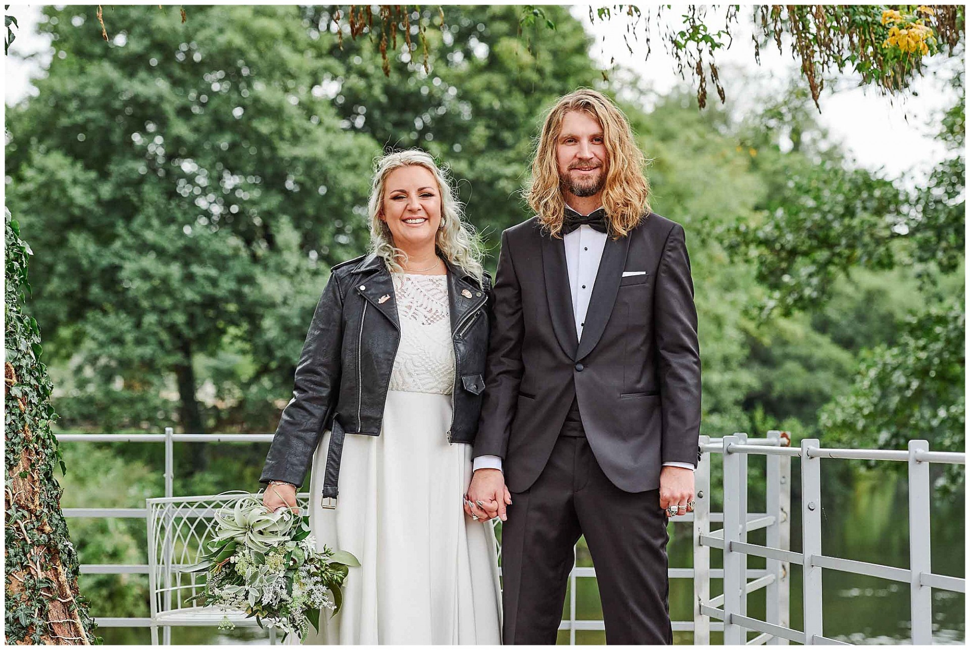 Rock and Roll style Bride and groom holding hands in front of green trees at the West Mill Wedding Venue in Derby