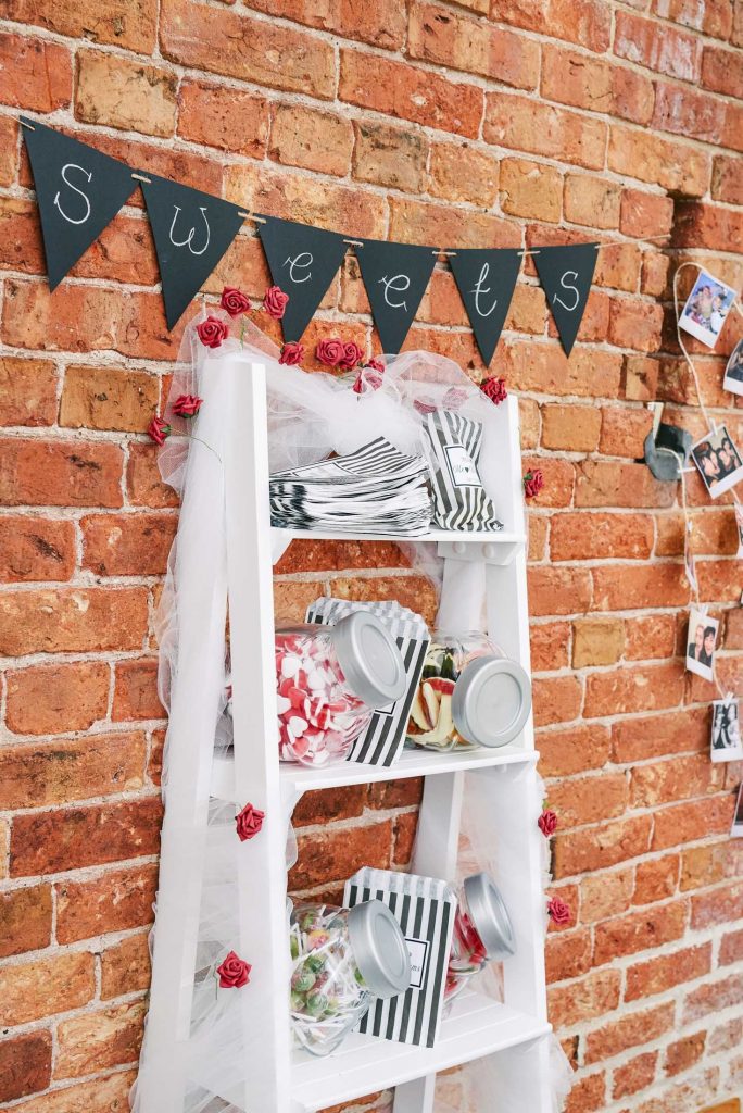 White sweet shelf against a brick wall at The Pheasantry Brewery wedding venue.