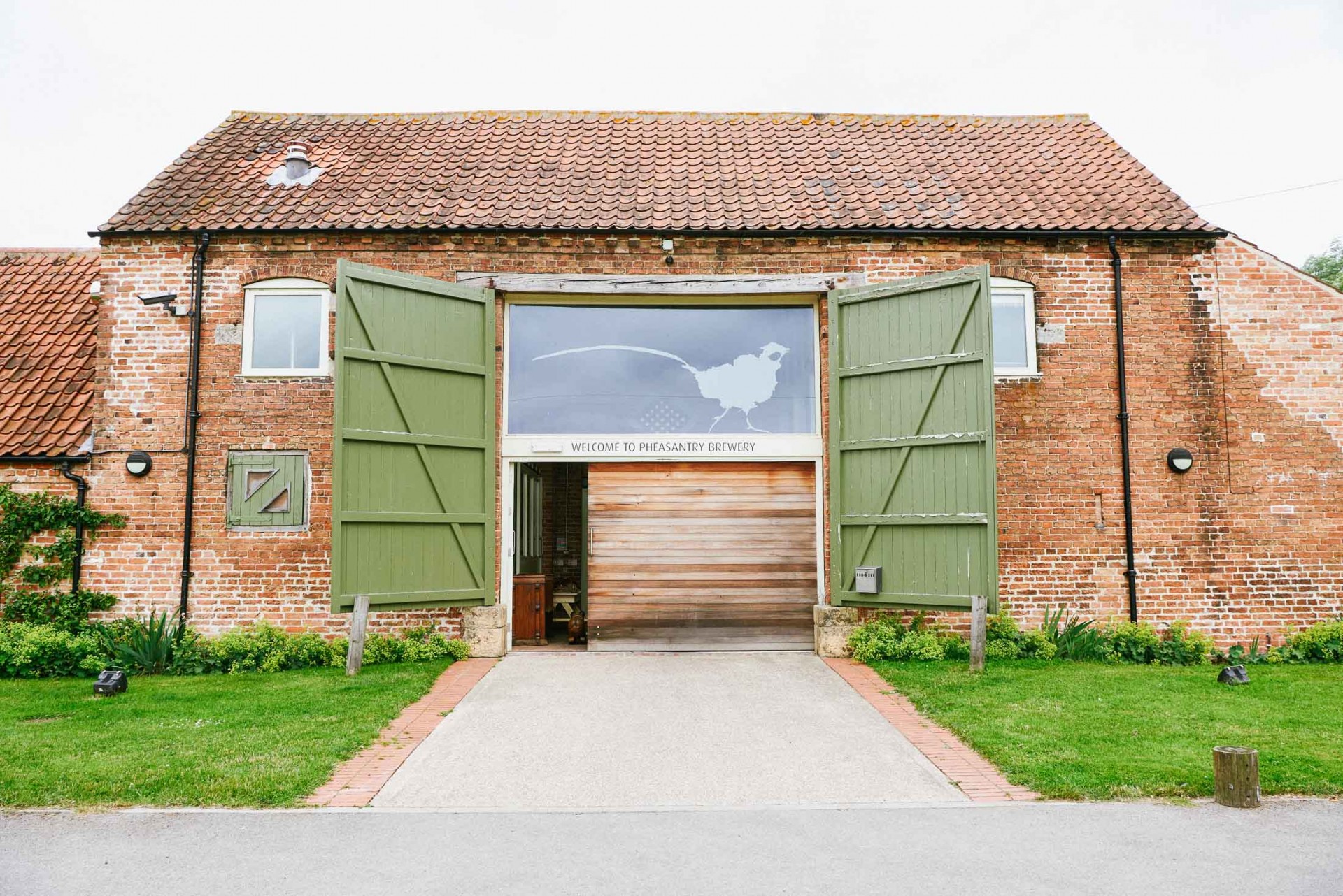 Exterior shot of the The Pheasantry Brewery wedding venue with it's barn doors open.