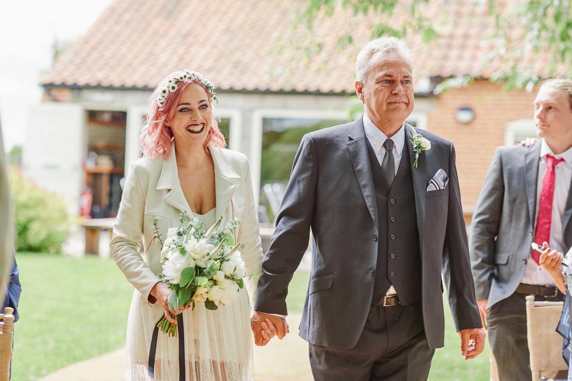 Festival style bride and her father walking down outside wedding aisle at The Pheasantry Brewery.