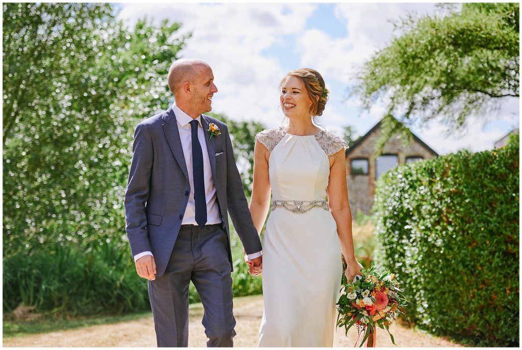 Bride and groom walking together and laughing in front of the Granary Estates barn