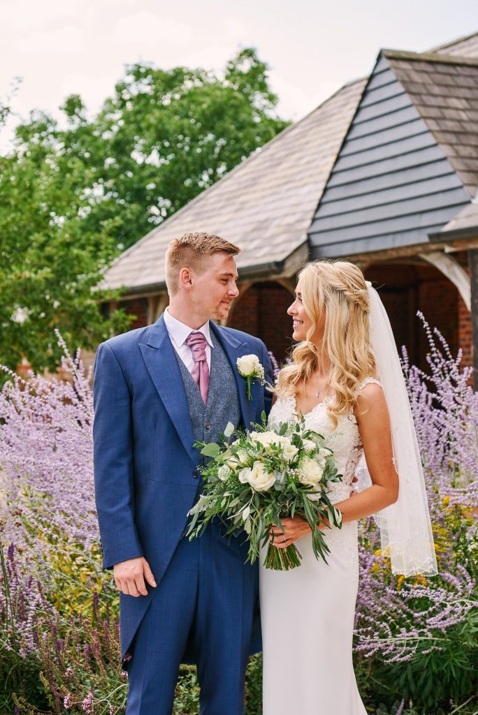 Bride and groom stood outside in front of beautiful lavender plants