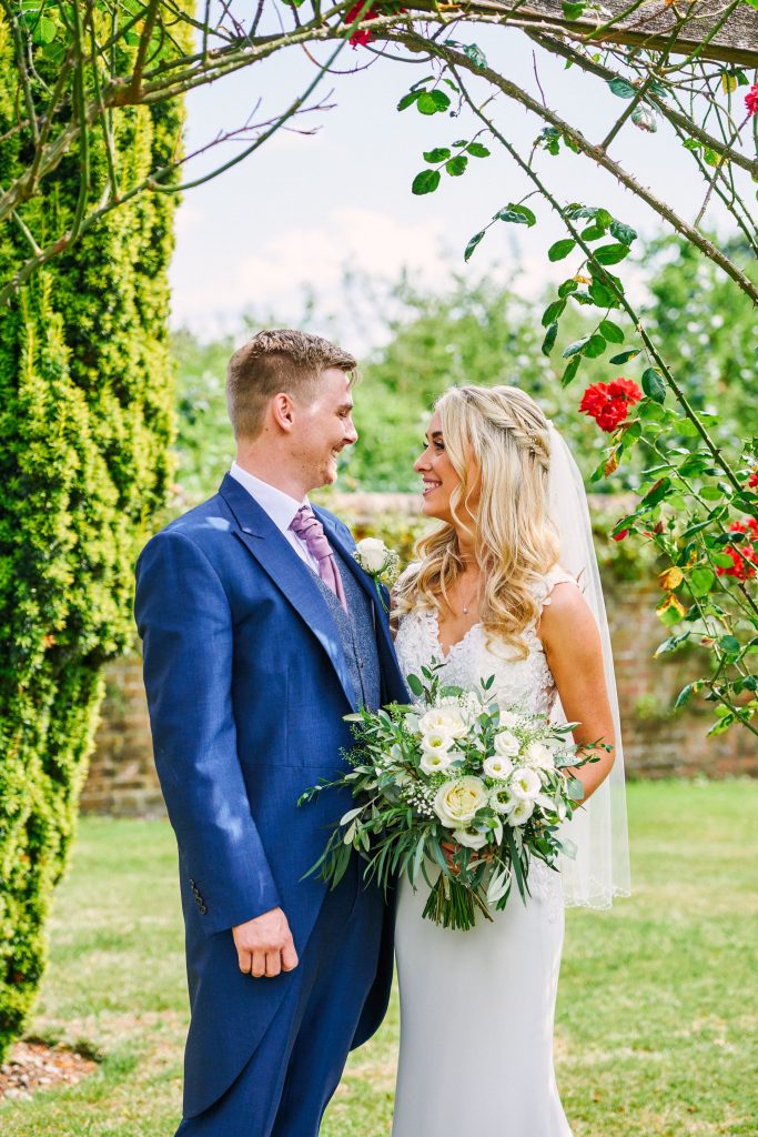 Bride and groom stood outside in a beautiful rose garden at Micklefield Hall