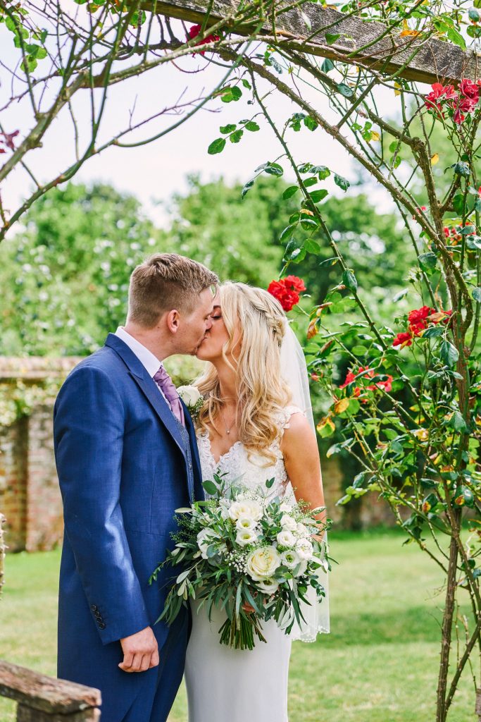 Happy bride and groom kissing outside in a beautiful rose garden