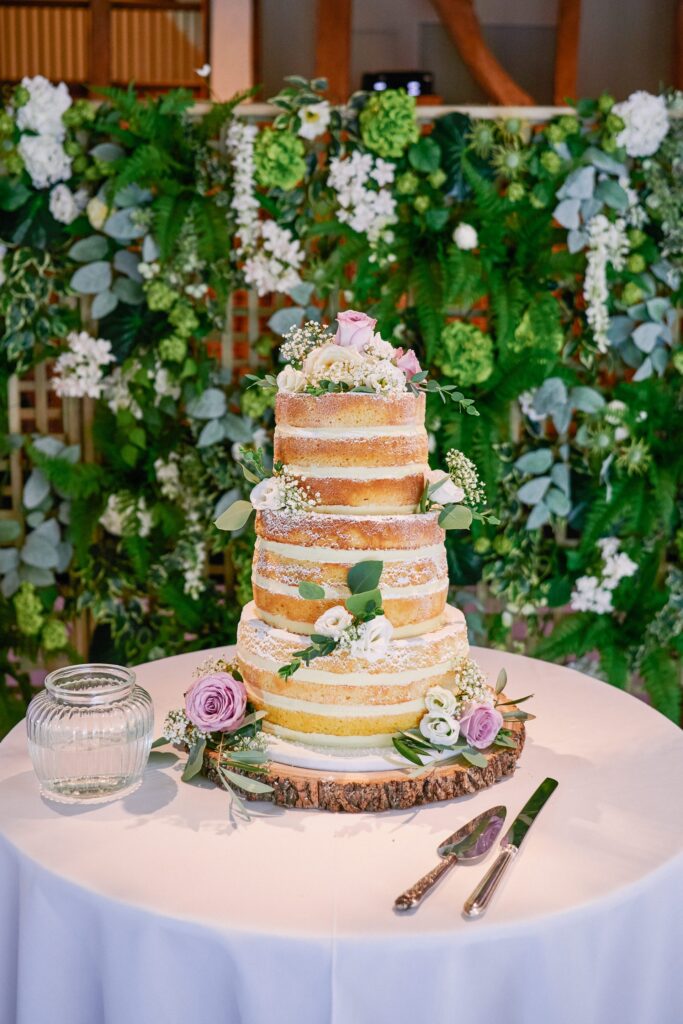Beautiful layered sponge wedding cake in front of floral background at Micklefield Hall