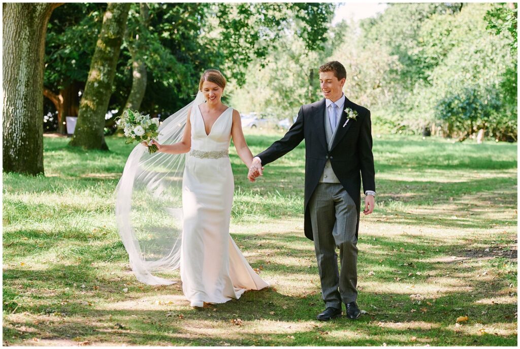 Bride and groom walking together and smiling during summer festival wedding at Pamber Place