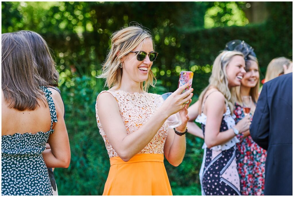Happy wedding guest taking a photo during a beautiful marquee wedding in Hampshire
