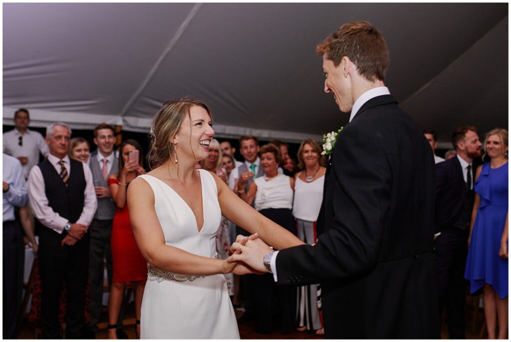 Wedding couple laughing and dancing during evening marquee reception