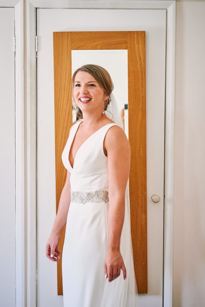bride laughing in front of mirror in her wedding dress