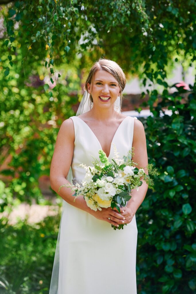 Bride holding beautiful flower bouquet in sunny garden 