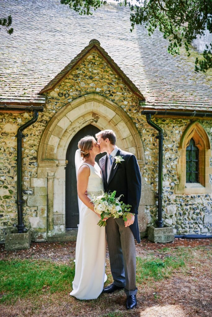 bride and groom kissing whilst stood in the sun