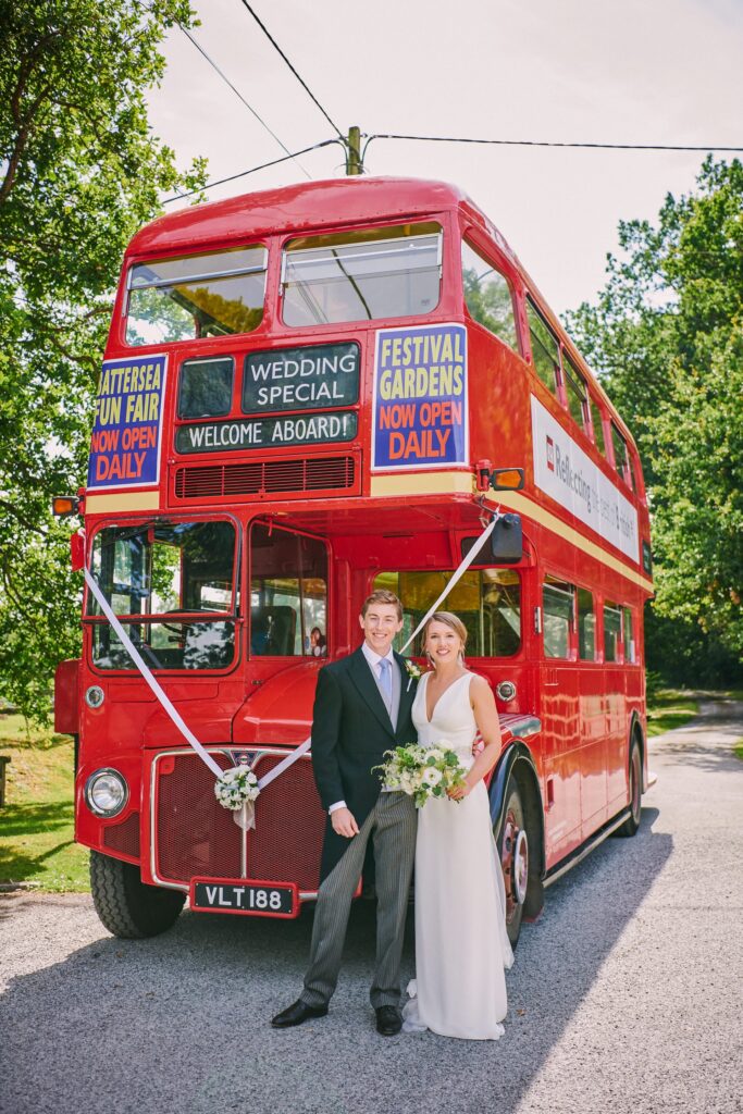beautiful wedding couple smiling in front of red London bus