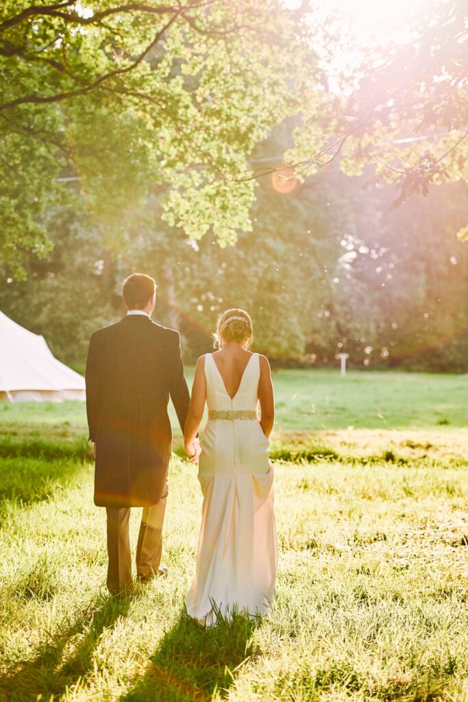 bride and groom walking together at sunset at their beautiful  festival wedding 