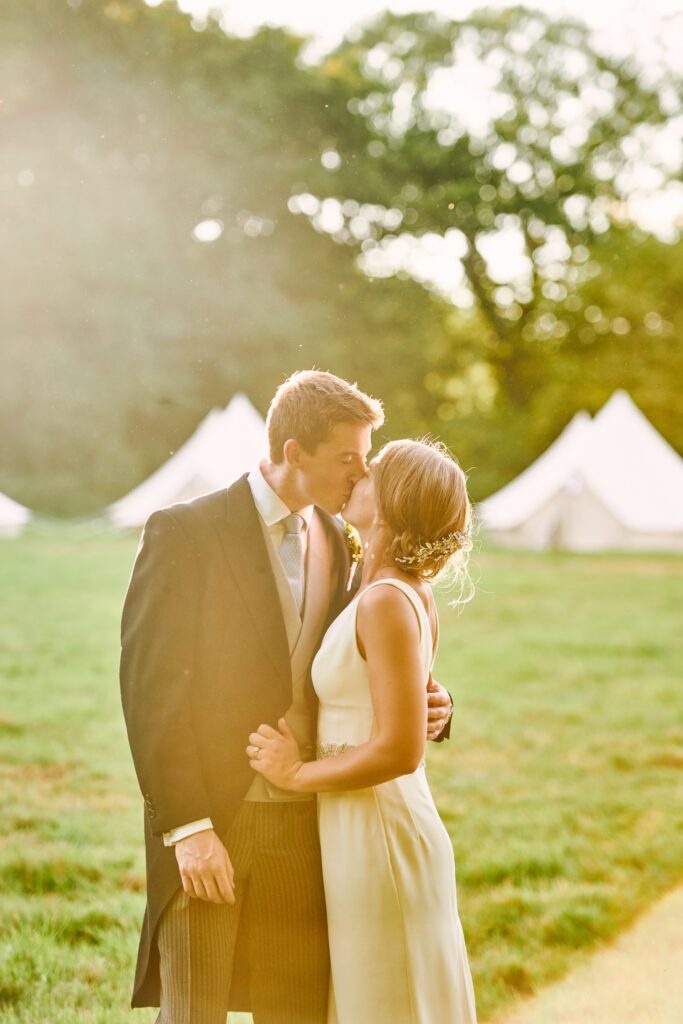 Wedding couple kissing during beautiful sunset at their festival themed wedding 