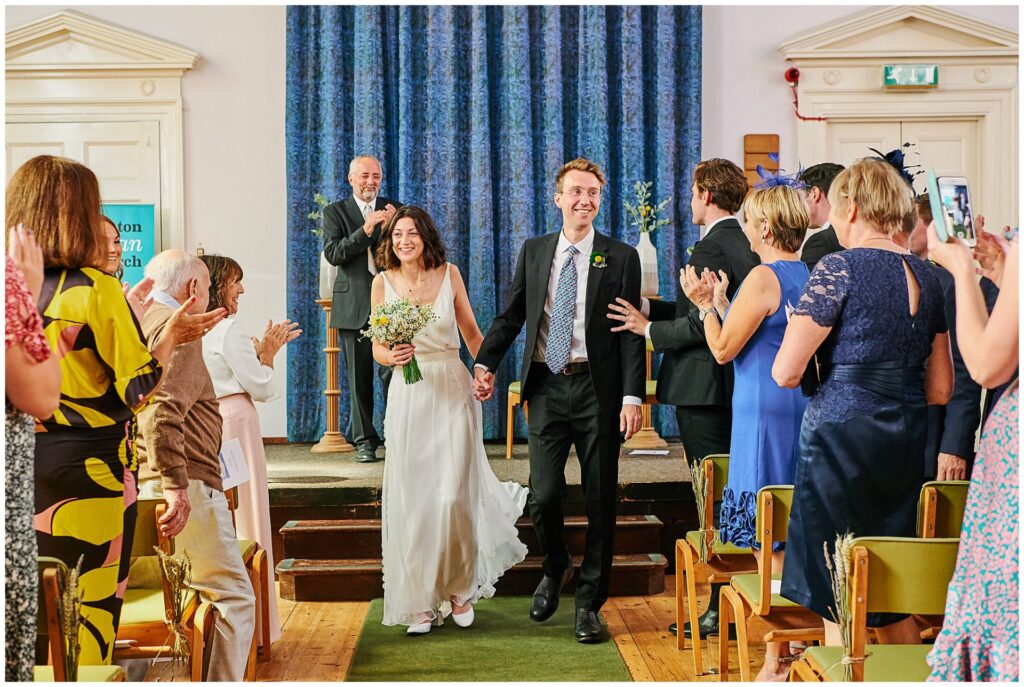 Bride and groom walking back down the isle during wedding ceremony in Brighton