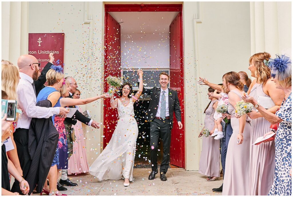 Bride and Groom walking through confetti outside Brighton Unitarian Church