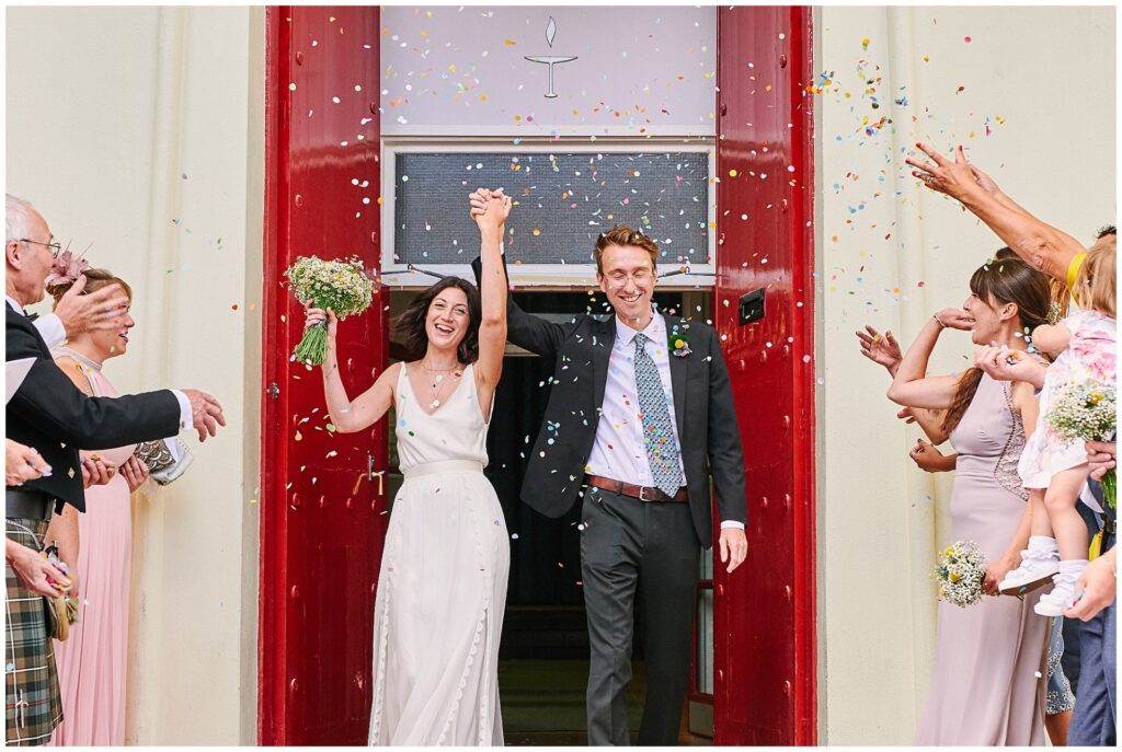 Bride and Groom walking through confetti outside Brighton Unitarian Church