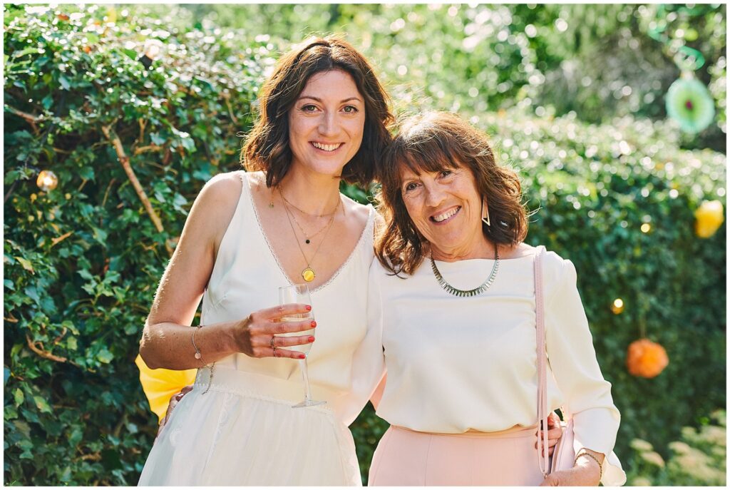 Bride and mum smiling together in Brighton garden on summers day 