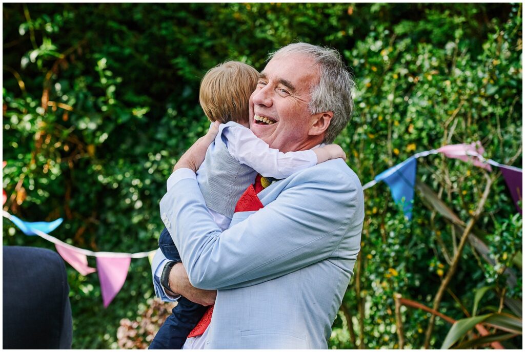 Wedding guest hugging child during garden party wedding reception 