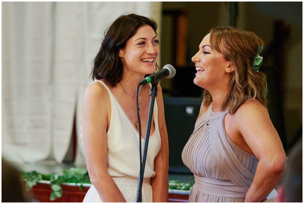 Bride singing with her bridesmaid during speeches 
