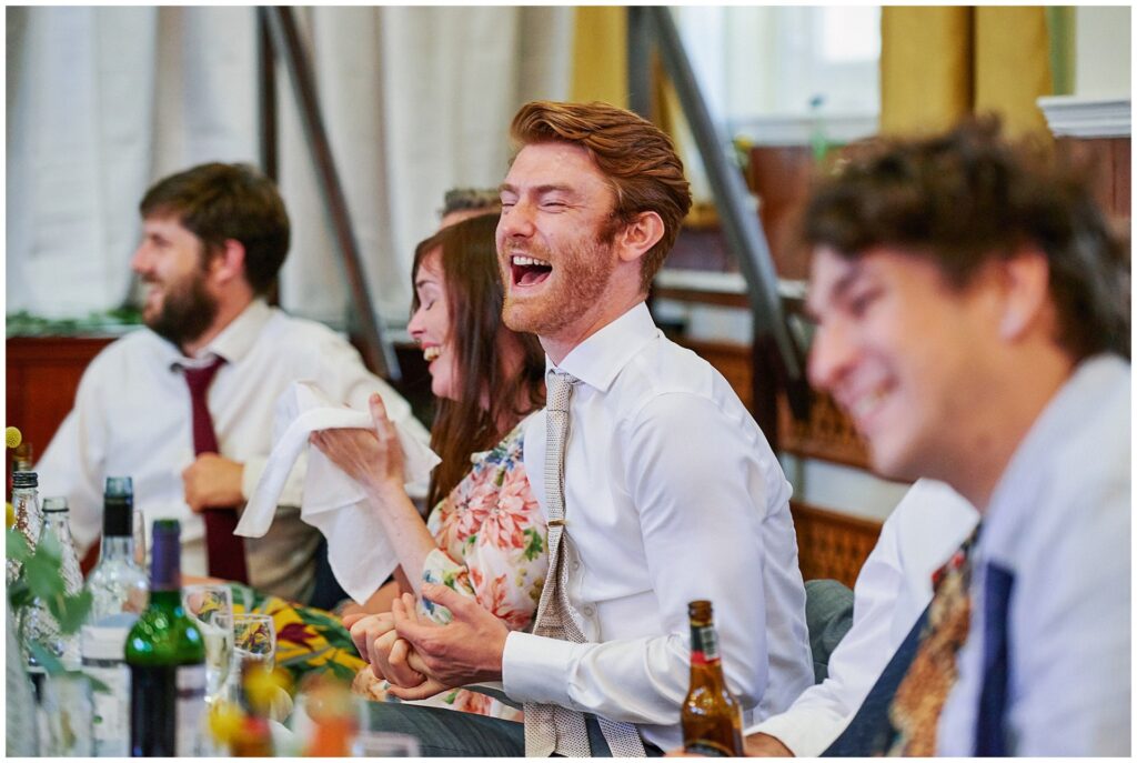 Guest laughing during wedding dinner speeches in Brighton. 
