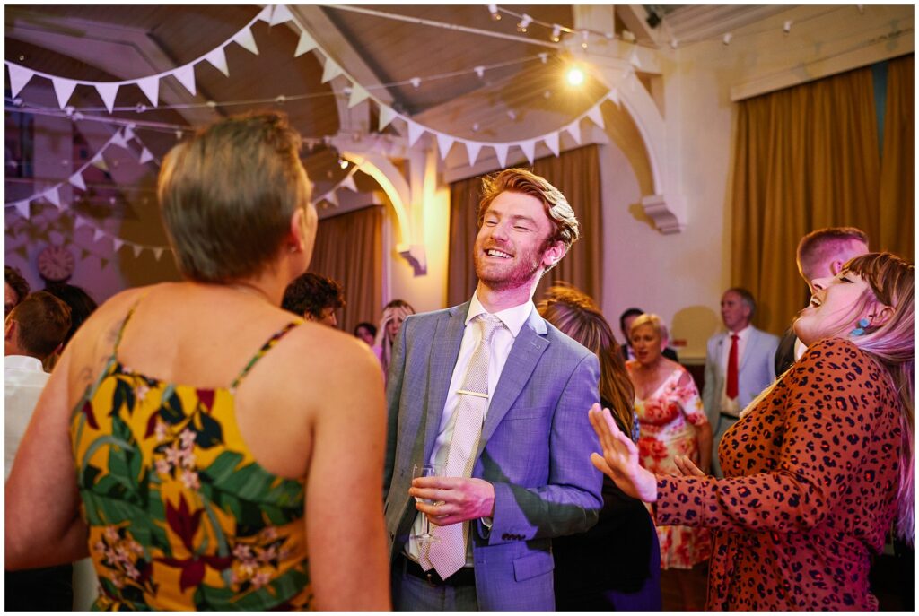 Happy wedding guests dancing during evening party in Brighton 