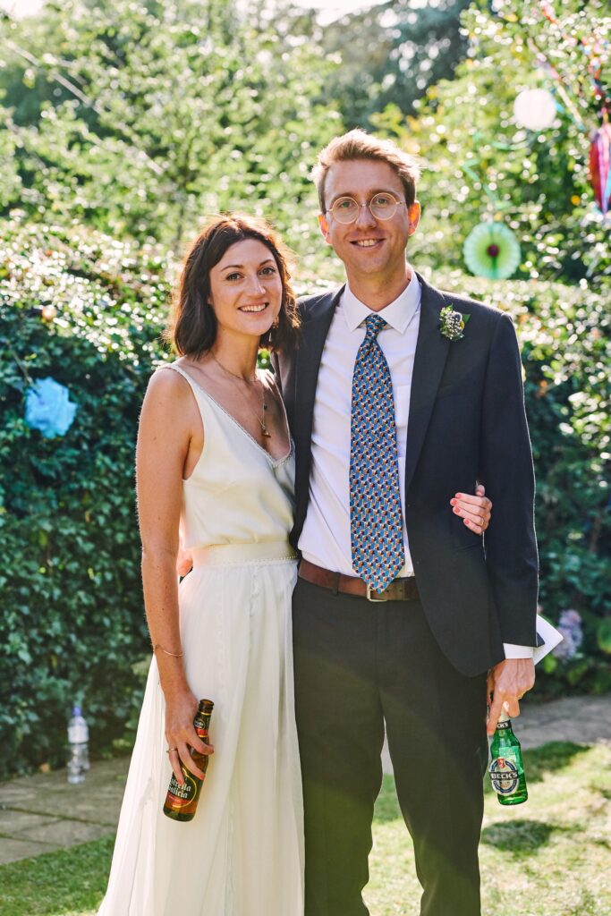 Bride and groom smiling together during their laid back summer wedding reception in Brighton. 
