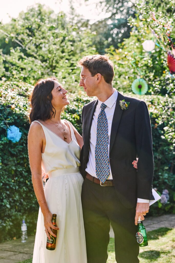 Bride and groom laughing together during summer garden party wedding reception in Brighton.